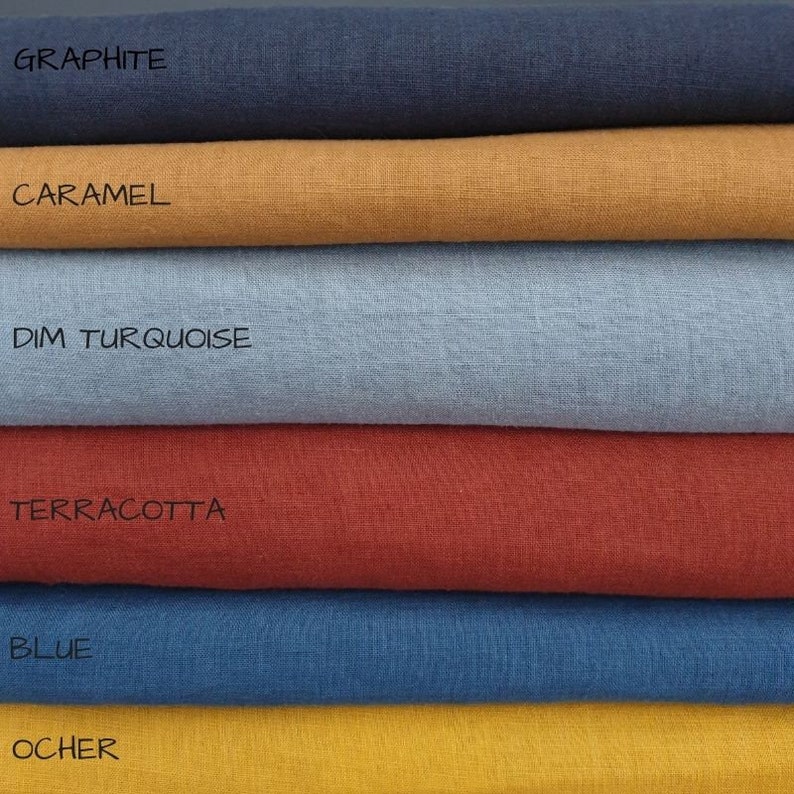 May include: Six fabric swatches stacked on top of each other. The swatches are in the following colors from top to bottom: graphite, caramel, dim turquoise, terracotta, blue, and ocher.
