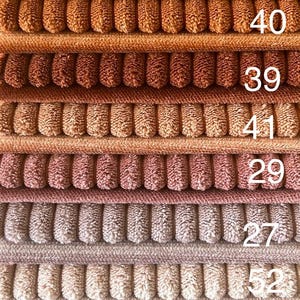 May include: A stack of 14 fabric swatches in various shades of brown, yellow, pink, gray, and black. The swatches are numbered 44, 43, 42, 41, 40, 39, 29, 27, 52, 55, 60, 34, and 135.