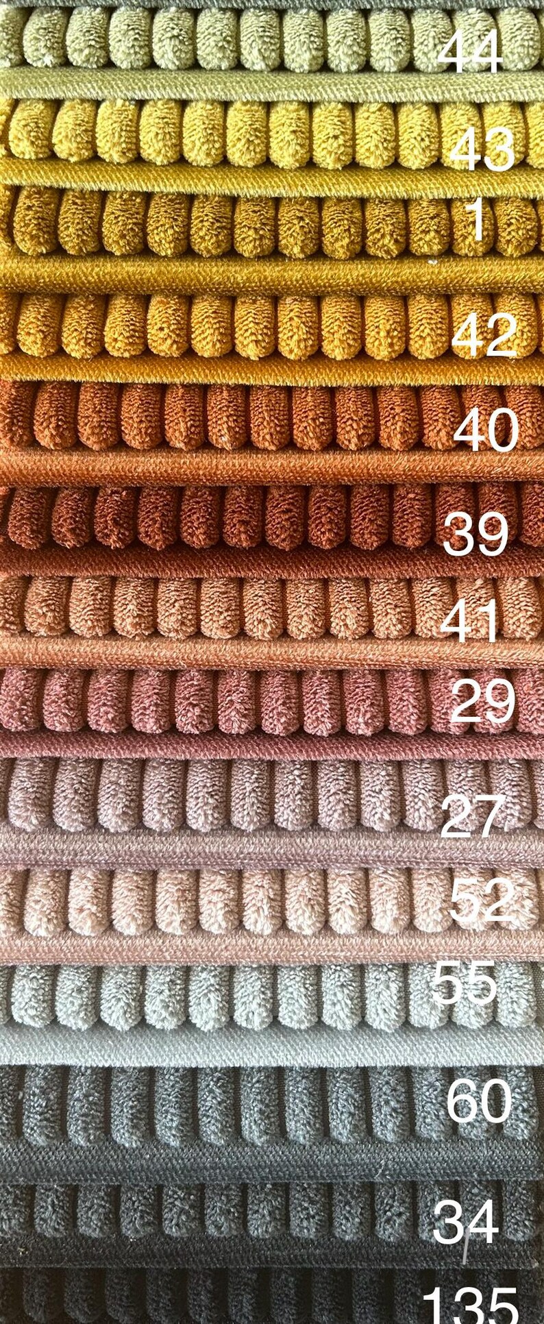 May include: A stack of 14 fabric swatches in various shades of brown, yellow, pink, gray, and black. The swatches are numbered 44, 43, 42, 41, 40, 39, 29, 27, 52, 55, 60, 34, and 135.