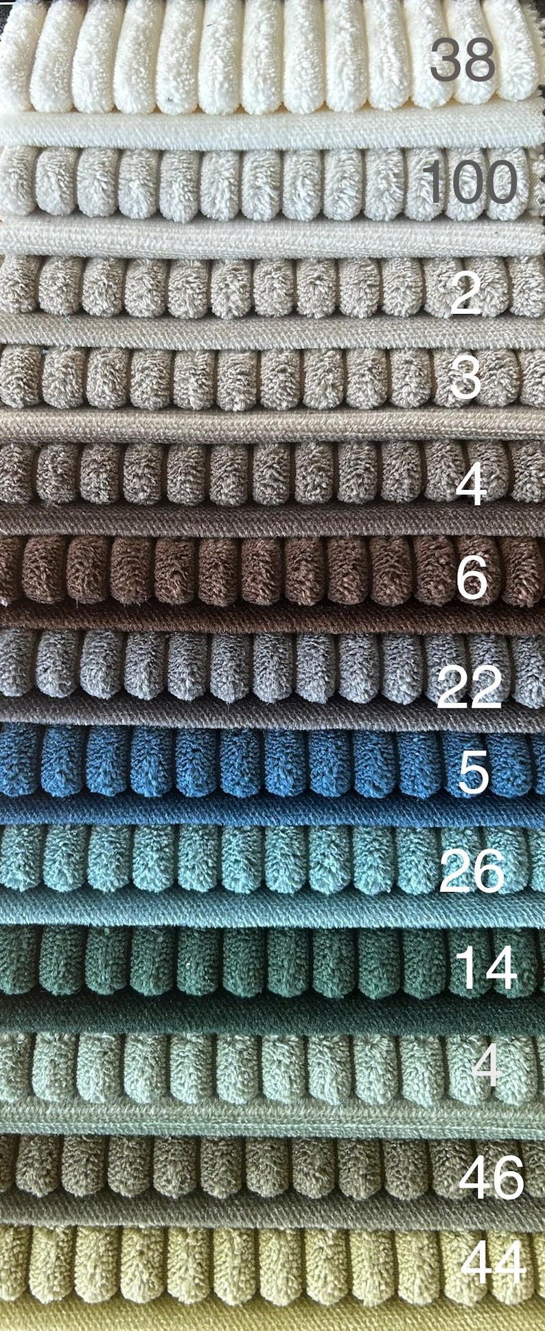 May include: A close-up of a stack of different colored corduroy fabrics. The fabrics are arranged in rows, with the numbers 38, 100, 2, 3, 4, 6, 22, 5, 26, 14, 4, 46, and 44 visible on the right side of the image.