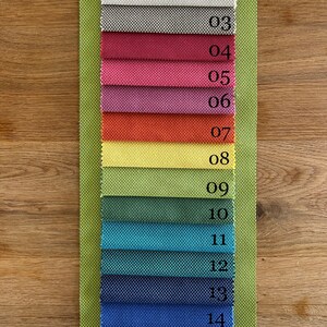 May include: A fabric swatch card displaying 16 different fabric samples. The samples are numbered 01 to 16. The fabric samples are in a range of colours and textures.