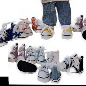 Könnte beinhalten: Eine Sammlung von Miniatur-Leinenschuhen in verschiedenen Farben, darunter Blau, Orange, Gelb, Lila und Weiß. Jeder Schuh hat weiße Schnürsenkel und eine weiße Gummisohle. Die Sneaker sind für Puppen oder andere kleine Figuren konzipiert.