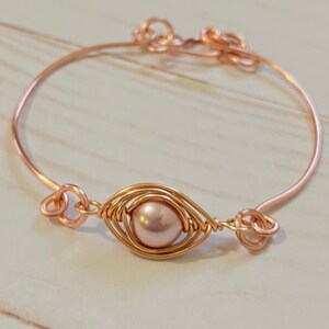 Peut inclure: Un bracelet jonc en fil de cuivre rose avec une seule perle enveloppée de fil. Le bracelet a un design simple et est parfait pour tous les jours.
