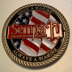 May include: A gold-colored coin with a black and white American flag design. The words "Once a Marine, Always a Marine" are inscribed around the edge of the coin. The words "Semper Fi" and "United States Marines" are also inscribed on the coin.