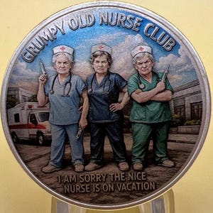 May include: A silver-colored coin with the words "GRUMPY OLD NURSE CLUB" around the top edge. The coin features three nurses in scrubs, holding syringes. The text "I AM SORRY THE NICE NURSE IS ON VACATION" is at the bottom.