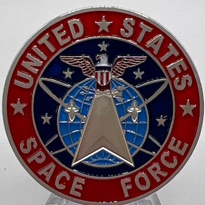 Könnte beinhalten: Eine silberne und blaue US Space Force Challenge-Münze mit rotem Rand. Die Münze zeigt einen Globus mit einem silbernen Pfeil nach oben, einen Weißkopfseeadler mit ausgebreiteten Flügeln und die Worte "United States Space Force".
