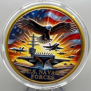 May include: A commemorative coin featuring a bald eagle with outstretched wings, an aircraft carrier, and fighter jets against a backdrop of the American flag and a sunset. The coin is inscribed with "U.S. NAVAL FORCES".