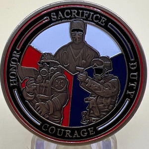 May include: A circular, bronze-toned coin with a red, white, and blue segmented design. The coin depicts a firefighter, a doctor, and a soldier. The words "HONOR", "SACRIFICE", "DUTY", and "COURAGE" are inscribed around the coin's edge.