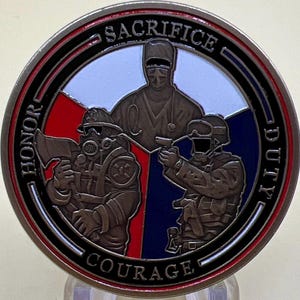 May include: A circular coin with a red, white, and blue design. It depicts a firefighter, a medic, and a soldier. The coin is inscribed with the words "HONOR", "COURAGE", "DUTY", and "SACRIFICE" around the edge. A commemorative item.
