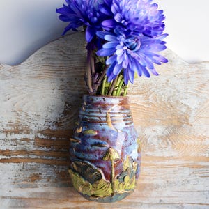 This unique rustic flower vase is inspired by magical woodland landscapes and features vibrant hand-glazed details of mushrooms and plants.
