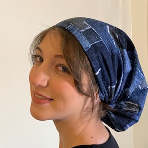 May include: A dark blue denim-patterned head covering. The fabric has a patchwork design with white and light blue accents. The head covering is worn on the head.