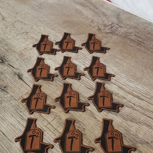 May include: Twelve brown leather patches with a black outline. Each patch features a stylized hammer and the text "02" in a white font.