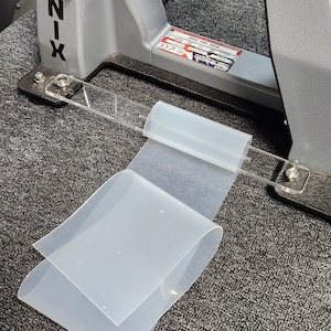 May include: Two clear silicone sheets are lying on a gray carpet. The sheets are folded in half and are slightly curved. The sheets are about 12 inches long and 6 inches wide.