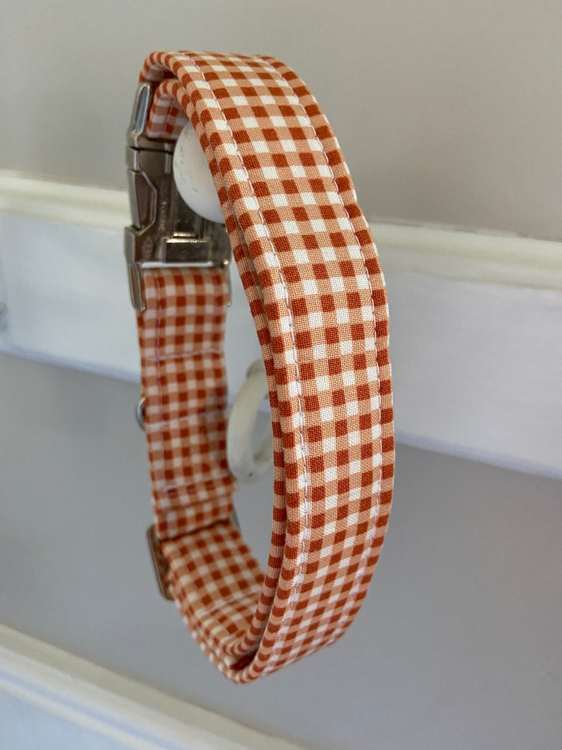 May include: A brown and white gingham dog collar with a silver buckle.