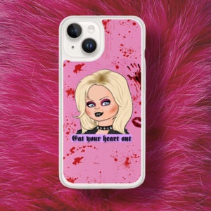 K&ouml;nnte beinhalten: Eine rosa Handyh&uuml;lle mit wei&szlig;em Rand. Die H&uuml;lle zeigt eine Comic-Illustration einer blonden Frau mit schwarzem Halsband und dem Text "Get your heart out". Der Hintergrund ist rosa mit roten Spritzern.