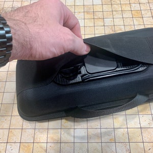 May include: A black zippered carrying case with a handle and a flap that opens to reveal a black interior with compartments.