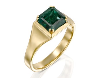 May include: A gold ring with a square emerald green gemstone set in a gold bezel.