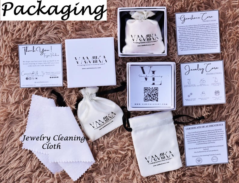 May include: White packaging for jewelry with the brand name "VAMIKA" printed on it. The packaging includes a small white drawstring bag, a jewelry cleaning cloth, a thank you card, a gemstone care card, a jewelry care card, and a certificate of authenticity.
