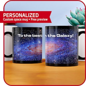 May include: Two black color-changing mugs with a galaxy design and the text "To the best in the Galaxy!" printed on them. The mugs are on a wooden surface.