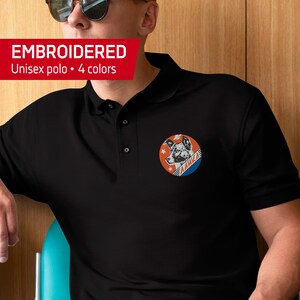 May include: Black embroidered unisex polo shirt with a red, white, and blue patch featuring a dog's head and the word "LAIKA" in Cyrillic script.
