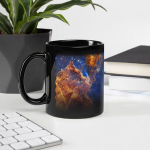 May include: Black ceramic coffee mug with a colorful image of a nebula, a cloud of gas and dust in space, printed on the front.