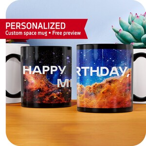 Puede incluir: Dos tazas de café negras con una imagen de nebulosa espacial. Una taza dice "HAPPY BIRTHDAY" y la otra dice "MY"