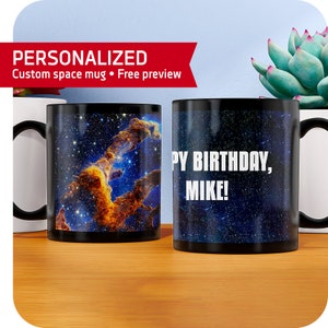 May include: Two black mugs with a space-themed design. One mug features a nebula with orange and blue colors. The other mug has the text "Happy Birthday, Mike!" in white.