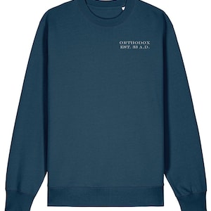 May include: A teal sweatshirt featuring the text "ORTHODOX EST. 33 A.D." in light grey. The garment has a crew neck and long sleeves, suitable for cooler weather.