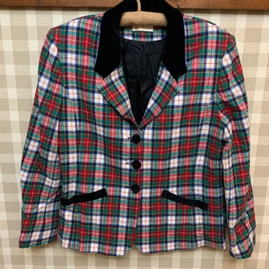 May include: A red, green, white, and blue plaid blazer with a black velvet collar. The blazer has a button closure and two pockets.