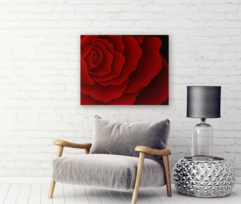 May include: A close-up of a single red rose with petals that are curled and layered. The rose is in focus, while the background is blurred.