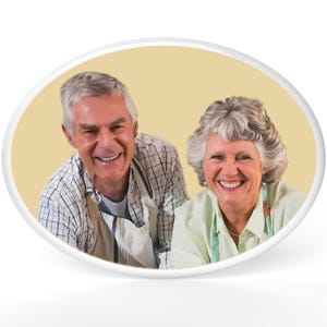May include: An oval-shaped image featuring a smiling older couple. The man wears a checkered shirt and apron, while the woman wears a light green top and apron. They are positioned against a light yellow background.