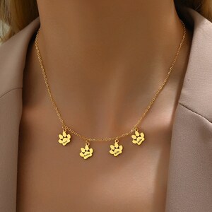 Può includere: Collana in oro con quattro ciondoli a forma di impronta di zampa, ognuno inciso con un nome diverso: Bear, Bailey, Bella e Bella.