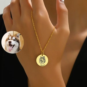 Puede incluir: Collar de oro con un colgante redondo con una imagen grabada en blanco y negro de la cara de un perro y el nombre "Bruno" debajo.