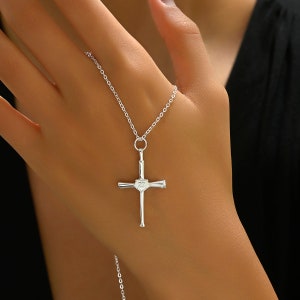 May include: Silver baseball bat cross necklace with a heart-shaped pendant. The pendant has the number 23 engraved on it.