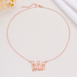May include: Rose gold necklace with three cat silhouettes, each with a name inscribed: Rosie, Franklin, and Penny.