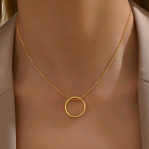 May include: A gold chain necklace with a simple circle pendant.