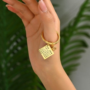 May include: Gold keychain with a small calendar charm featuring the month of April 2024. The charm has a small heart and a clear crystal stone.
