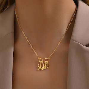May include: Gold necklace with two cat silhouettes, each with a name inscribed on the back. The names are "Pumpkin" and "Penny".