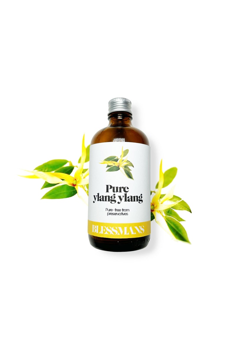 May include: A brown glass bottle with a silver lid, labeled "Pure ylang ylang" and "Pure-free from preservatives" with the brand name "Blessmans" printed below. The bottle is surrounded by yellow flowers with green leaves.