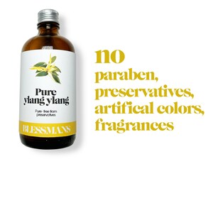 May include: A brown glass bottle with a silver lid, labeled "Pure ylang ylang" and "Blessmans". The bottle contains a natural essential oil. The text "no paraben, preservatives, artificial colors, fragrances" is written in yellow on a white background.