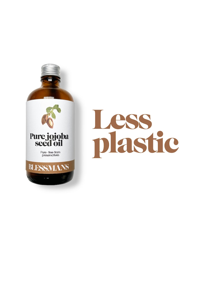 May include: A brown glass bottle with a silver lid and a white label that reads "Pure jojoba seed oil" and "Blessmans". The bottle is sitting on a white background with the text "Less plastic" in brown letters.