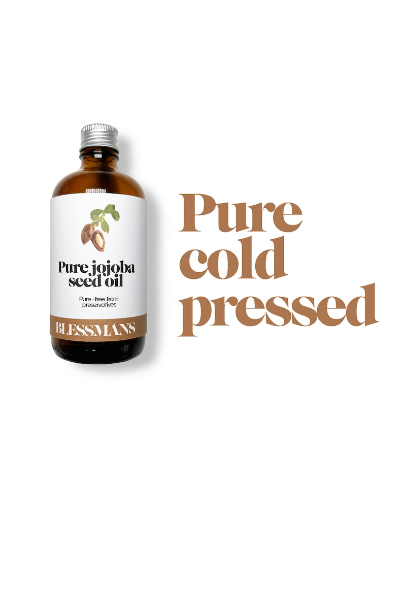 May include: A brown glass bottle with a silver lid, labeled "Pure jojoba seed oil" and "Blessmans". The bottle is sitting on a white background with the text "Pure cold pressed" in brown letters.