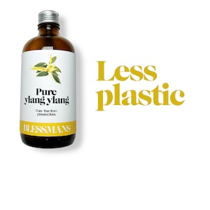 May include: A brown glass bottle with a silver lid and a white label. The label says "Pure ylang ylang" and "Pure - free from preservatives". The bottle is sitting on a white background with the text "Less plastic" in yellow letters.