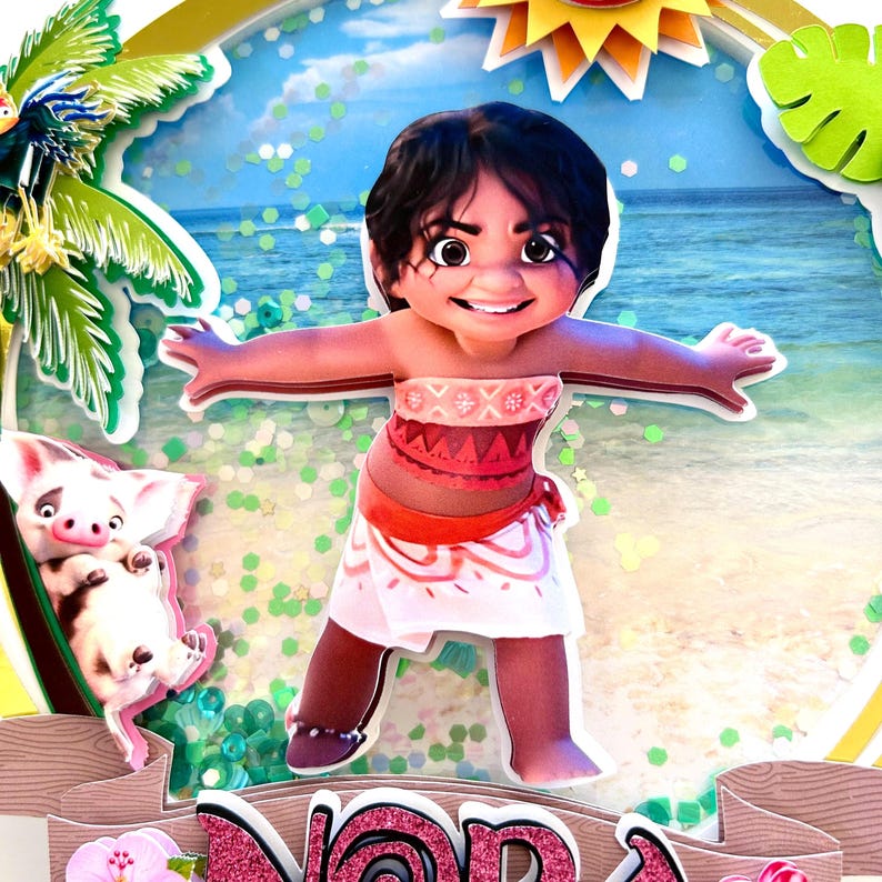 May include: A 3D cake topper featuring Moana from the Disney movie Moana. Moana is wearing a red and white patterned top and a pink and orange skirt. She is standing on a beach with a blue ocean and a palm tree in the background. The cake topper also includes a small pig.
