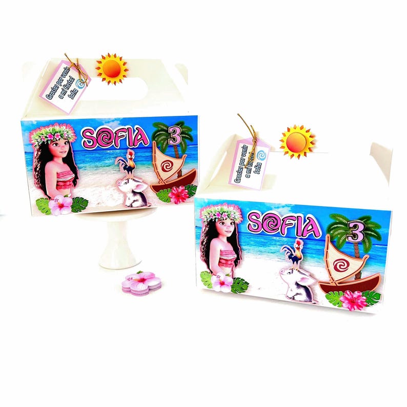 May include: Two white party favor boxes with a colorful design featuring a cartoon girl, a rooster, and a sailboat. The boxes have the name "Sofia" and the number "3" on them. A small sun and a tag are attached.