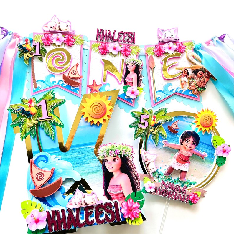 May include: A colorful cake topper set featuring Moana and Maui characters from the Disney movie Moana. The set includes a large letter "O" with a blue ocean background, a smaller letter "N" with a pink and blue banner, and a smaller letter "E" with a pink and blue banner. The set also includes a small cake topper with Moana and a small cake topper with Maui. The cake topper set is perfect for a Moana themed birthday party.