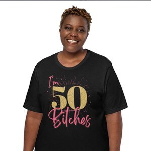 Puede incluir: Camiseta negra con un gr&aacute;fico de "I'm 50 Bitches" en purpurina dorada.