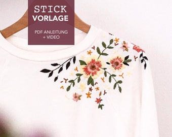 May include: White sweatshirt with a floral embroidery design on the shoulder. The embroidery features pink, red, yellow, and green flowers and leaves. The text "STICK VORAGE" is printed on the top of the sweatshirt, with the text "PDF ANLEITUNG + VIDEO" printed below.