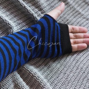 以下が含まれることがあります： 黒と青のストライプの腕カバーで、黒いカフが付いています。腕カバーは柔らかく伸縮性のある生地で作られています。