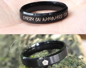 May include: Black ring with the engraved text "CARRY ON WAYWARD SON". The ring is shown in two different views. One view shows the text, and the other view shows a symbol. The ring is on a person's hand and on a mossy rock.